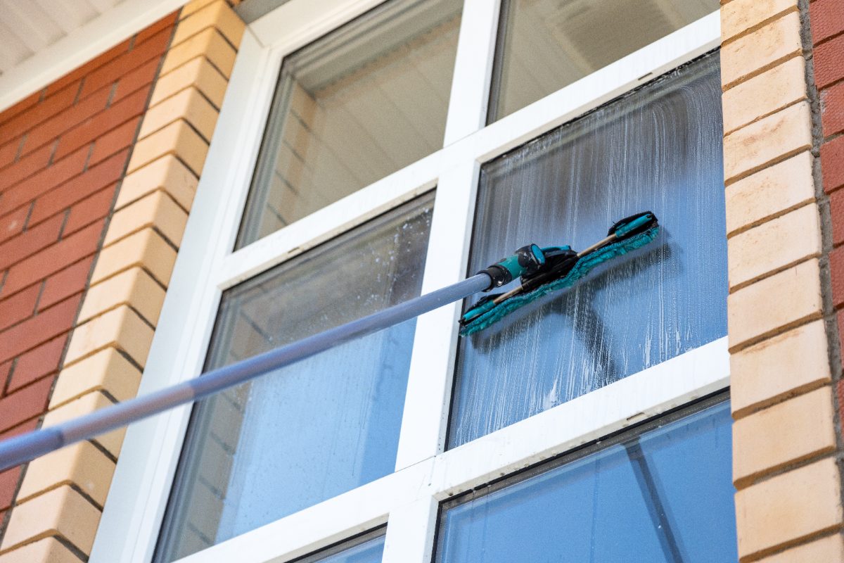 Professional window cleaning with water-fed pole on modern building facade